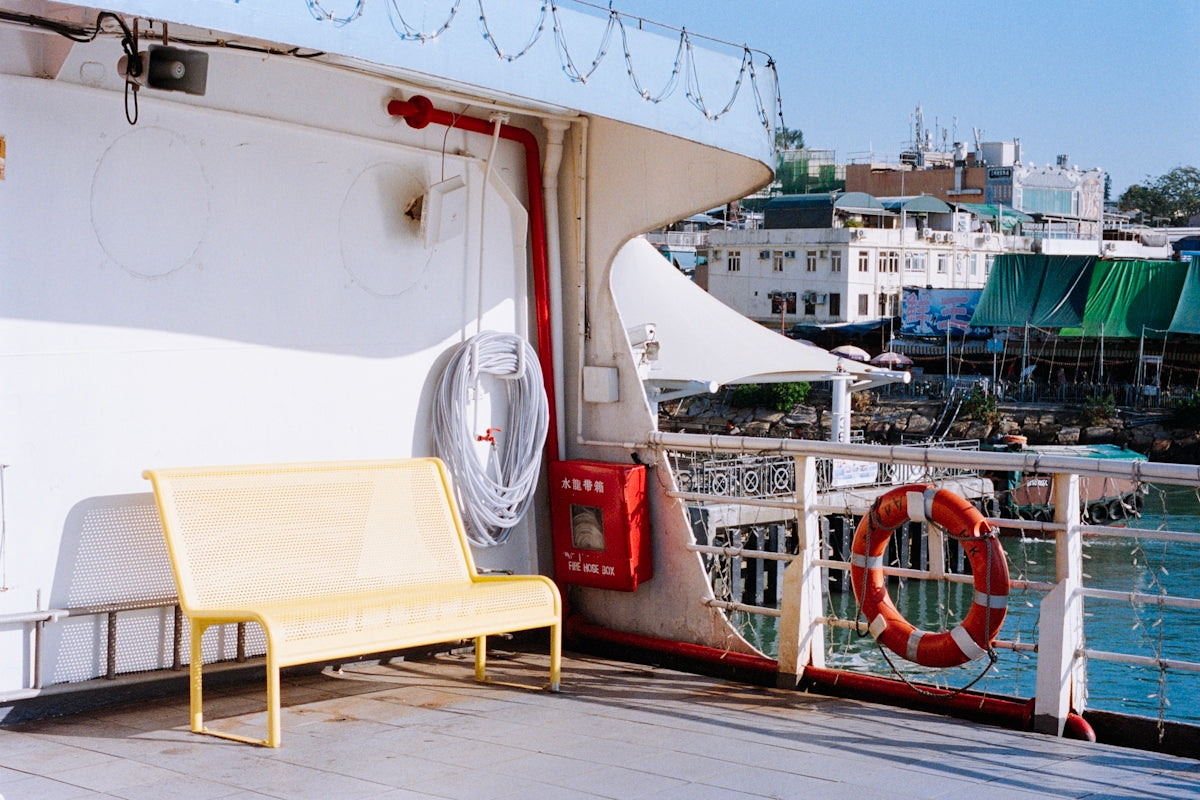 Yellow bench on a ferry deck with city view.